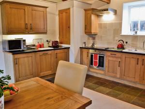 a kitchen with wooden cabinets and a wooden dining table at Penno Cottage - 24440 in Bodmin