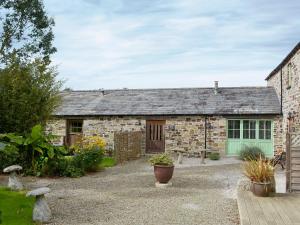 an old stone building with a green door in a yard at Penno Cottage - 24440 in Bodmin