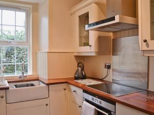 a kitchen with a sink and a stove at Horsepark Cottage in Girthon