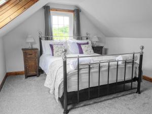 a bedroom with a bed with white and purple pillows at Horsepark Cottage in Girthon