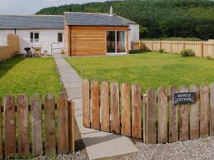 um quintal com uma cerca de madeira e uma placa em Myrtle Cottage - 28177 em Fairgirth