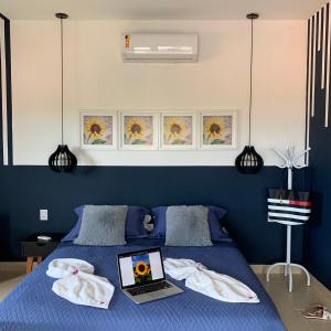 1 dormitorio con cama azul y ordenador portátil en Casa dos Girassóis, en Pipa
