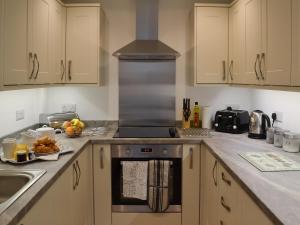 a kitchen with a stove top oven next to a sink at Little Longmead in Findon