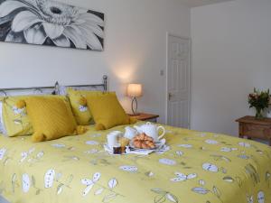 a yellow bed with a plate of food on it at Little Longmead in Findon