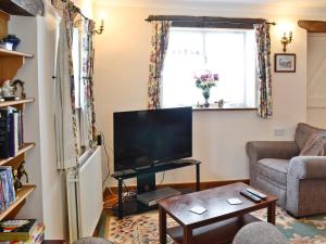 a living room with a tv and a couch and a table at Gingerbread Cottage in Fairford