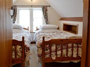 two twin beds in a room with a window at Gingerbread Cottage in Fairford