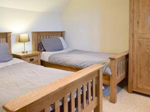 a bedroom with two beds and a bench in it at Bryncrwn Cottage in Rhyd-y-felin