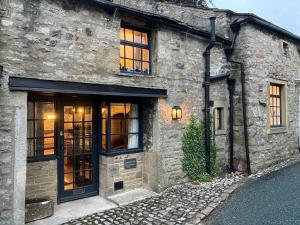 a stone building with windows and a door at Inglenook Cottage in Kettlewell