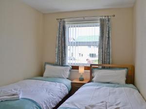 two beds in a small room with a window at Rowanlea Cottage in Nairn