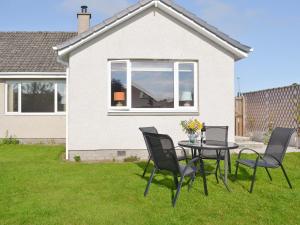 a table and chairs in the yard of a house at Rowanlea Cottage in Nairn