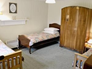 1 dormitorio con 2 camas y armario de madera en Glentairre Cottage - Swww, en Balnaboth
