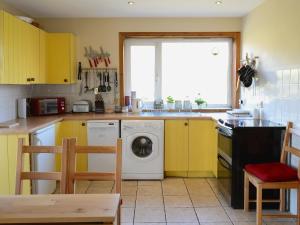 a kitchen with yellow cabinets and a washing machine at Cor An Easan in Talmine