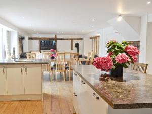 a kitchen and dining room with pink flowers on a counter at Burfields Barn in Rickinghall