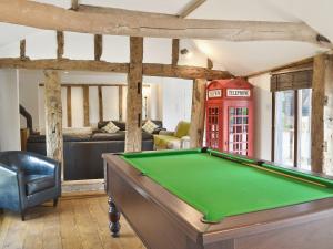 a room with a pool table and a red phone booth at Burfields Barn in Rickinghall