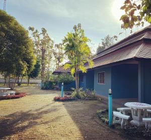 a blue building with a picnic table and a tree at LPL Resort in Chiang Mai