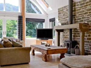 ein Wohnzimmer mit einem Kamin und einem TV in der Unterkunft Oak Lodge in Saint Fillans