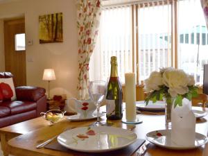 una mesa de comedor con una botella de vino y flores en The Smithy - Op6, en Carmarthen