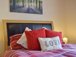 a bed with red pillows and a painting on the wall at The Smithy - Op6 in Carmarthen