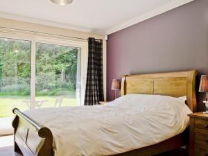 ein Schlafzimmer mit einem großen Bett und einem Fenster in der Unterkunft Oak Lodge in Saint Fillans