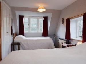 1 dormitorio con 2 camas y 2 ventanas en The Mill en Lindridge