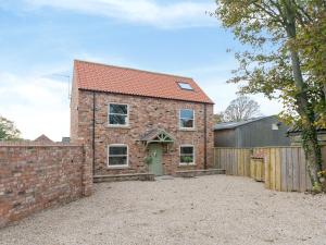 a brick house with a gate and a fence at Barn Owl Cottage in Skidby