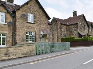 ein Backsteinhaus mit einem Zaun vor einer Straße in der Unterkunft Dove Cottage in Great Rowsley