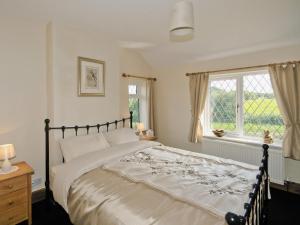 Un dormitorio con una cama grande y una ventana en Tomfield Cottage, en Kingsley