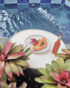 a plate of fruit on a table next to a swimming pool at Villa CACAO in Rivière-Salée