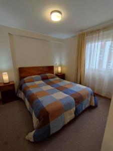 een slaapkamer met een groot bed in een kamer met een raam bij Departamento amoblado muy cómodo in Puerto Montt