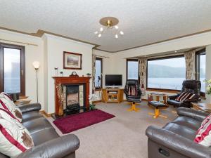 een woonkamer met een open haard en een televisie bij Loch Duich Cottage in Inverinate