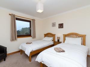 twee bedden in een kamer met een raam bij Loch Duich Cottage in Inverinate