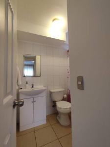 een witte badkamer met een toilet en een wastafel bij Departamento amoblado muy cómodo in Puerto Montt