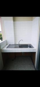 a sink with a faucet in a white tiled kitchen at We Residence Studio in Pattaya Central