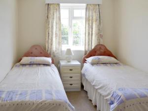 two twin beds in a room with a window at Dene Corner in Stokenham