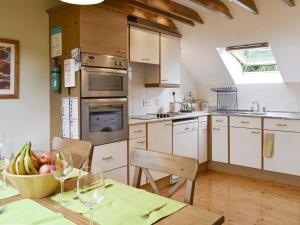 eine Küche mit einem Tisch mit einer Schale Obst und Weingläsern in der Unterkunft Osprey Cottage in Dunkeld