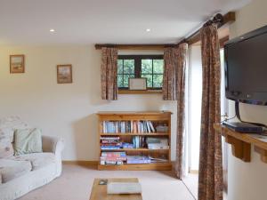 a living room with a couch and a tv at Clyst William Barn in Plymtree