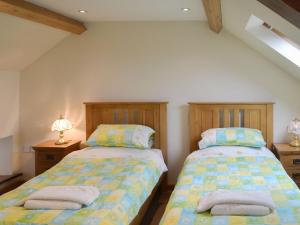 two beds sitting next to each other in a bedroom at Clyst William Barn in Plymtree