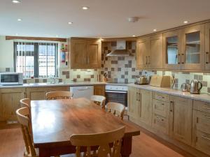 a kitchen with a wooden table and a table and chairs at Clyst William Barn in Plymtree