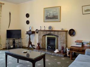a living room with a fireplace and a table at Gallt Y Balch in Llangadwaladr