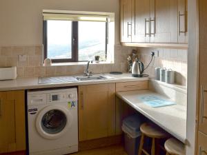 a kitchen with a washing machine and a sink at Nield Bank Bungalow in Flash