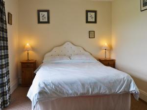 a bedroom with a white bed with two lamps at Gallt Y Balch in Llangadwaladr