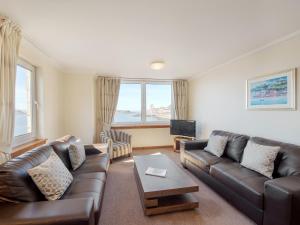 a living room with a leather couch and a tv at No 5 Esplanade Court in Oban