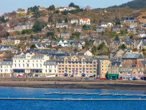 a city with buildings and boats in the water at No 5 Esplanade Court in Oban