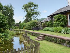 a garden with a pond in front of a house at The Station Masters House in Torver