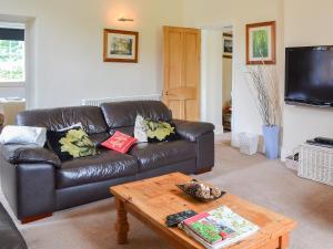 a living room with a leather couch and a coffee table at The Station Masters House in Torver