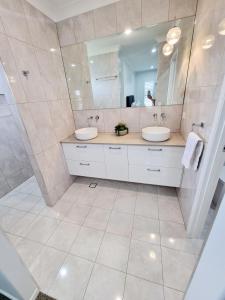 a bathroom with two sinks and a large mirror at Large and Private Executive Home - Secure parking for boats in Hervey Bay