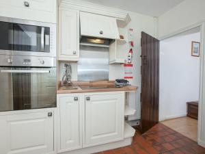 a kitchen with white cabinets and a counter top at Fir Tree Cottage in Standon