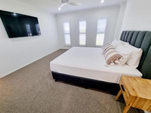 a white bedroom with a bed and a table at Large and Private Executive Home - Secure parking for boats in Hervey Bay