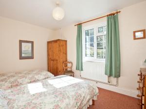 a bedroom with two beds and a window at Fir Tree Cottage in Standon