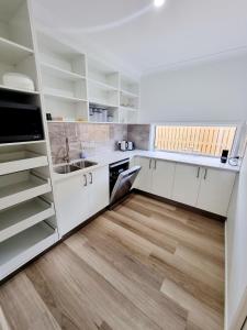 cocina con armarios blancos y suelo de madera en Large and Private Executive Home - Secure parking for boats en Hervey Bay